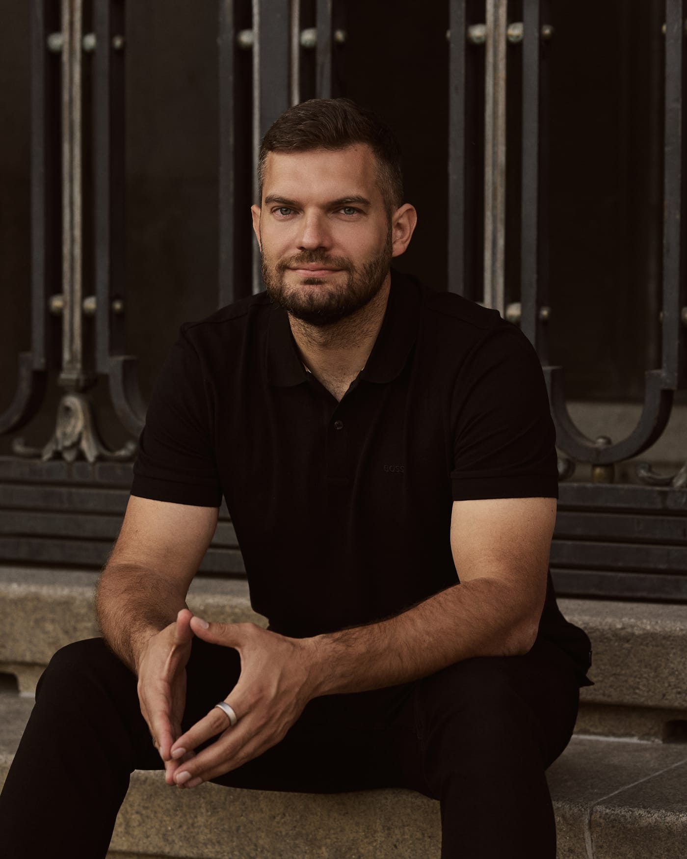 Illia Smoliienko sitting on stone steps in front of a wrought-iron gate